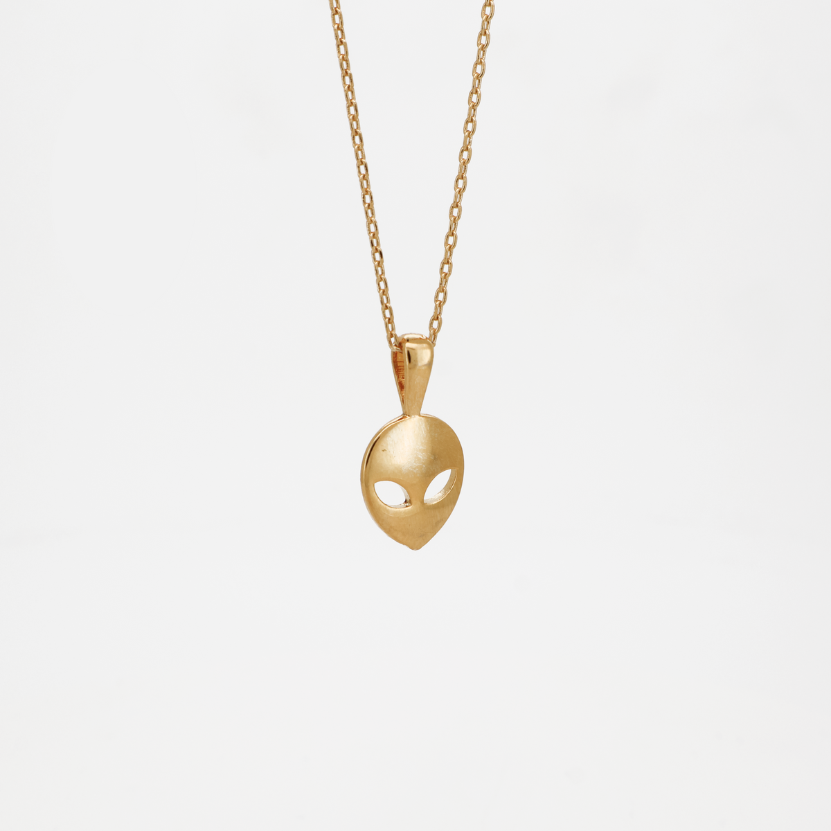 Gold alien head pendant necklace with smooth polished finish, photographed on a white background.