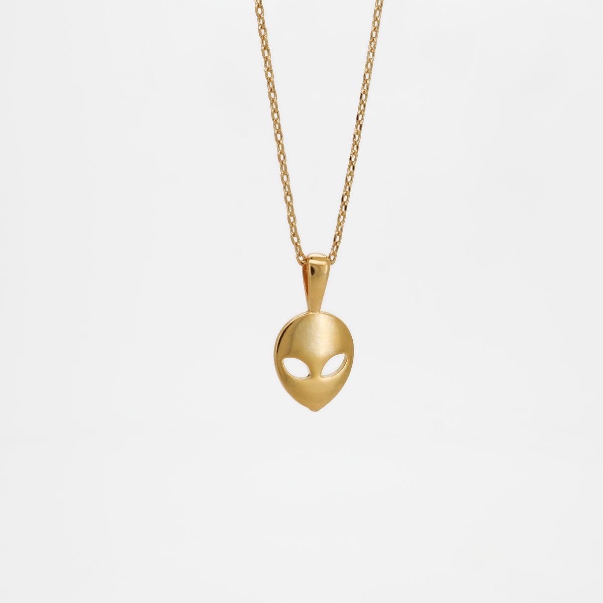 Gold alien head pendant necklace with smooth polished finish, photographed on a white background.