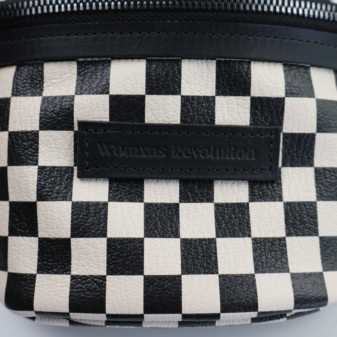 Close up on front of bum bag with black and white checkered leather. 