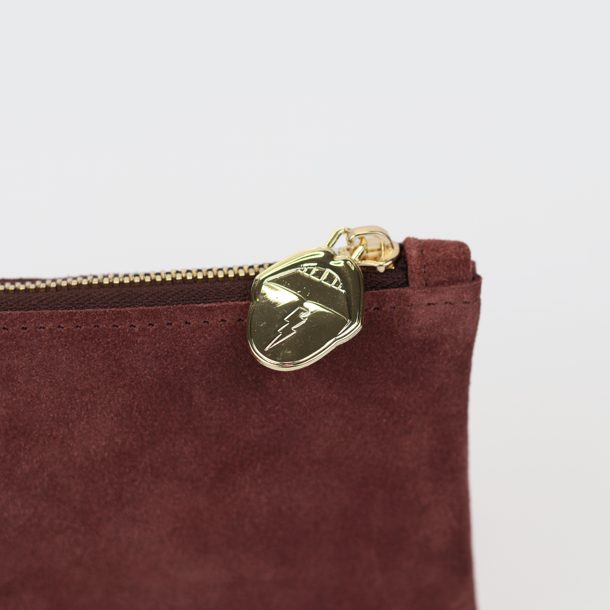 Close-up of gold zipper pull on mauve suede coin pouch