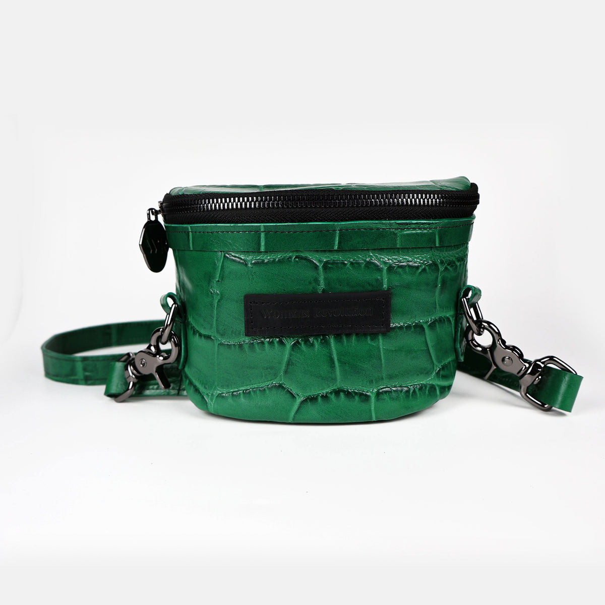 A green crocodile press leather Amara Petite Bum Bag with a zipper closure, a shoulder strap, and the brand 'Womxn's Revolution' visible on the front.
