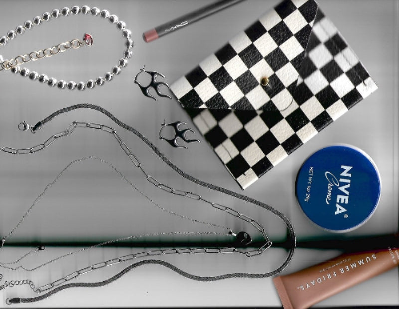Checkered pouch, necklace, lip balm, and Nivea product on a gray surface