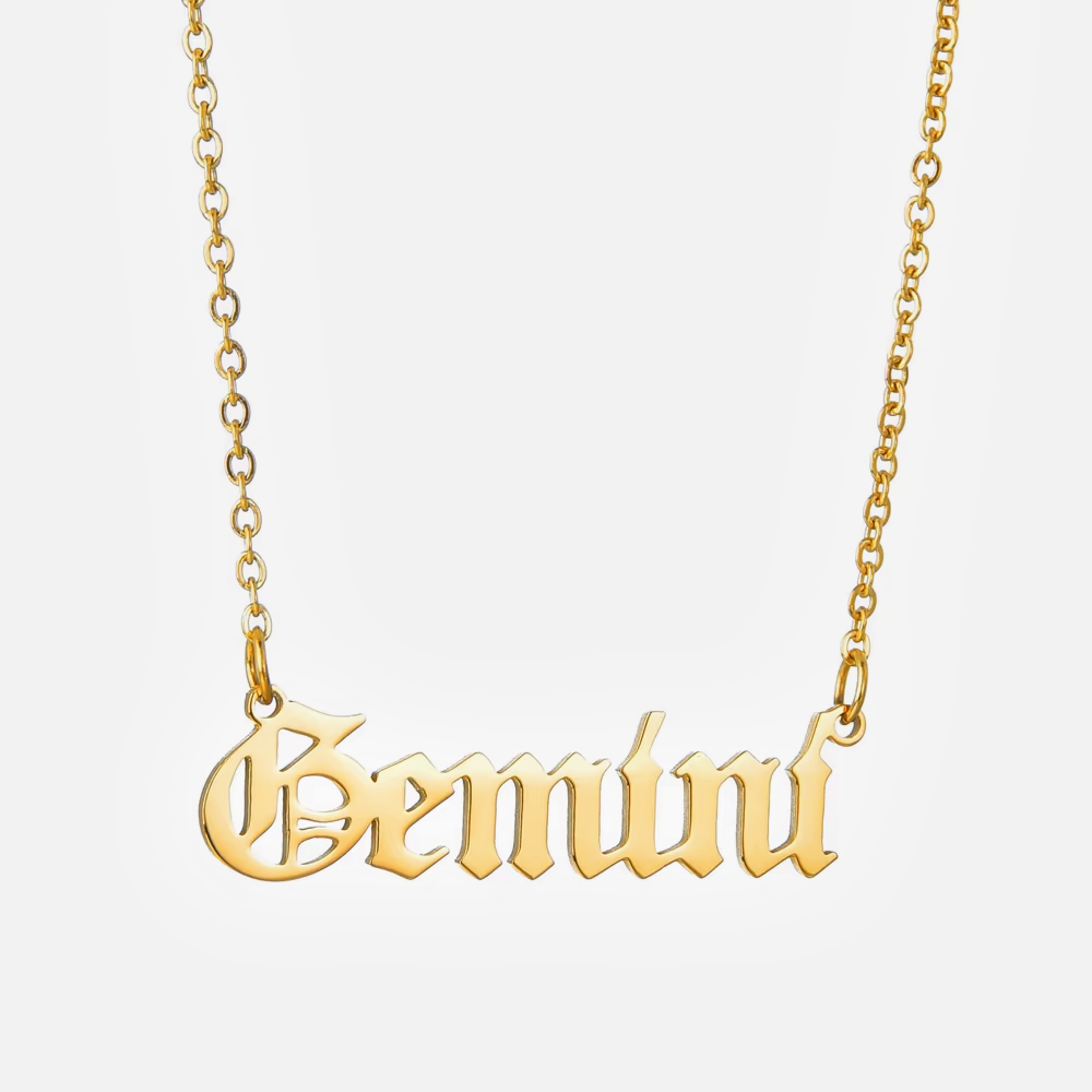A gold-plated necklace with the word 'Gemini' inscribed in a gothic font on a chain with a 2-inch extender.