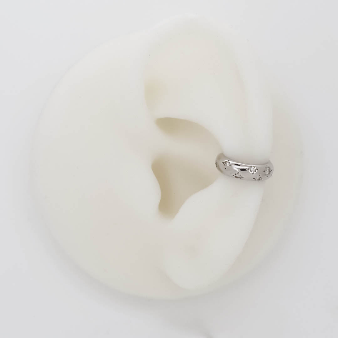 Silver ear cuff with small star-shaped crystal details, shown on an ear display.