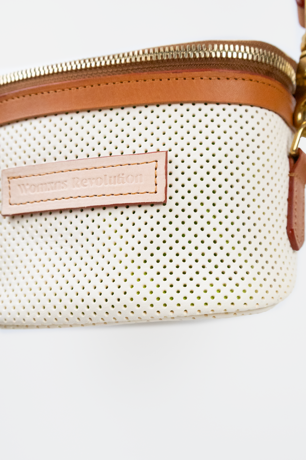 Perforated ivory bag with brown zipper and strap on a white background