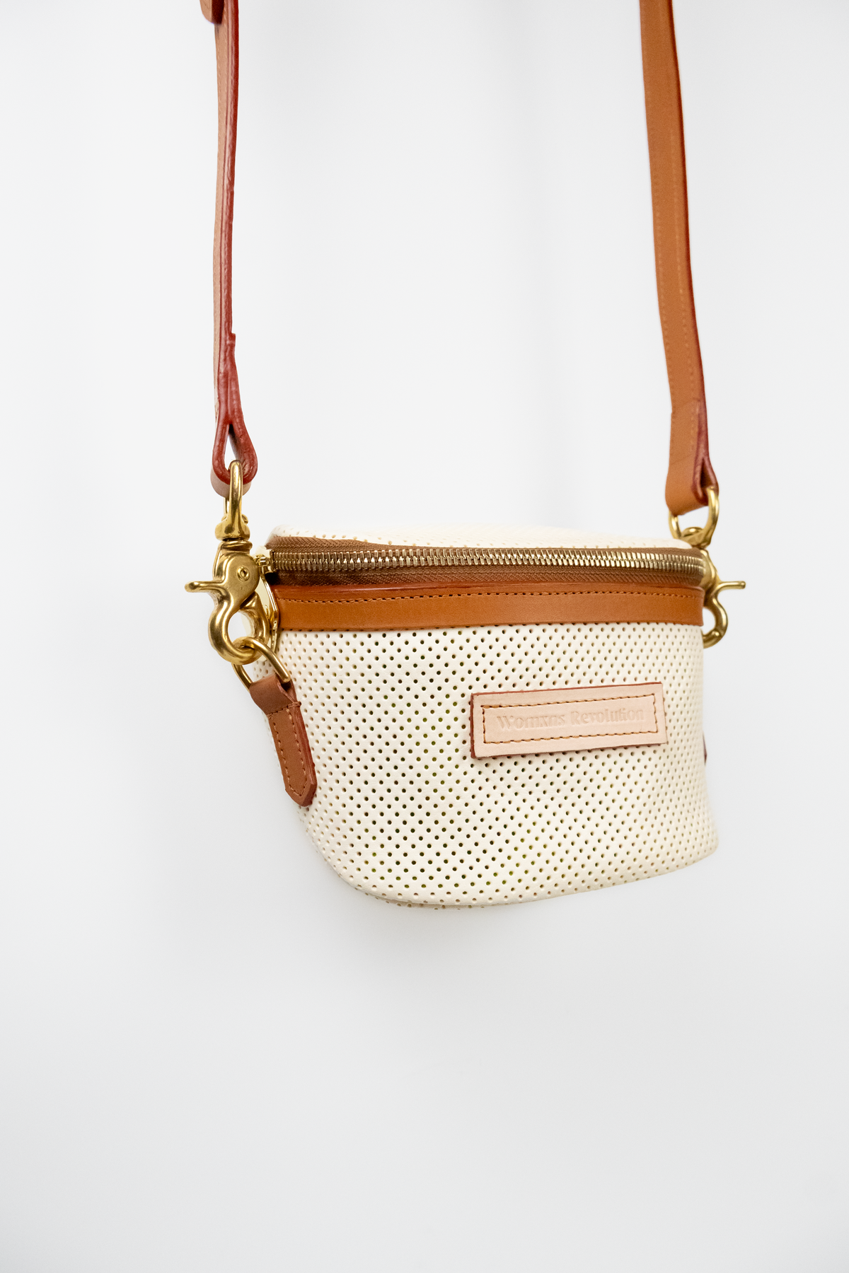 Perforated Ivory crossbody bag with brown strap on a white background