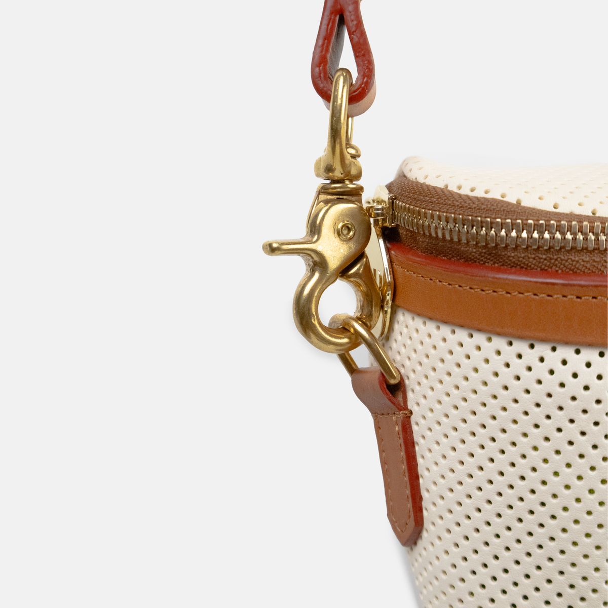 Close-up of a beige handbag with gold clasp and brown leather accents on a white background