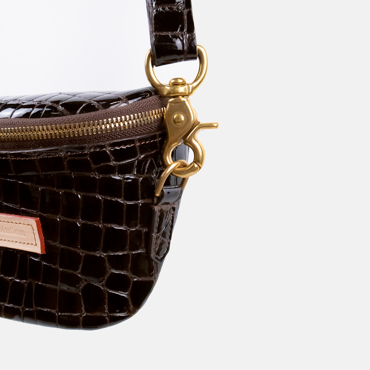 Dark Brown textured handbag with gold zipper and clasp on a light gray background