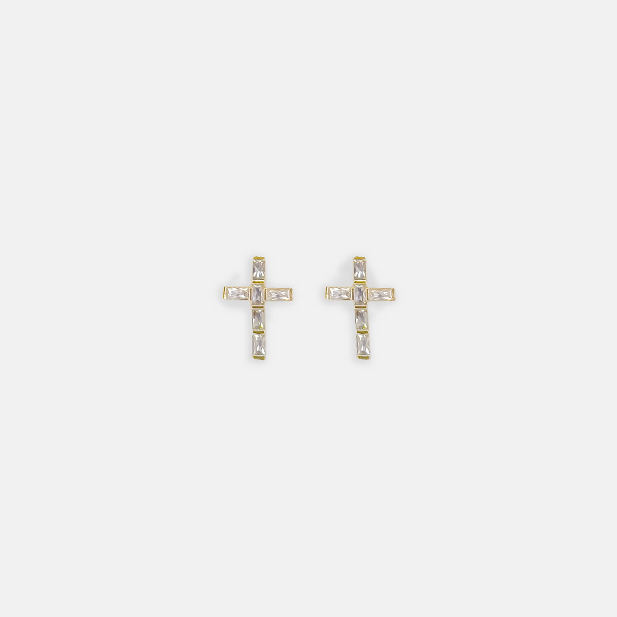 Pair of gold cross stud earrings set with clear baguette-cut crystals on a white background.