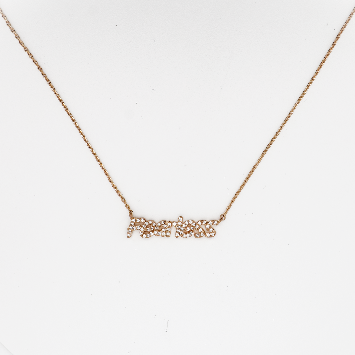 Gold ‘Fearless’ nameplate necklace with crystal accents on a delicate chain, photographed on a white background