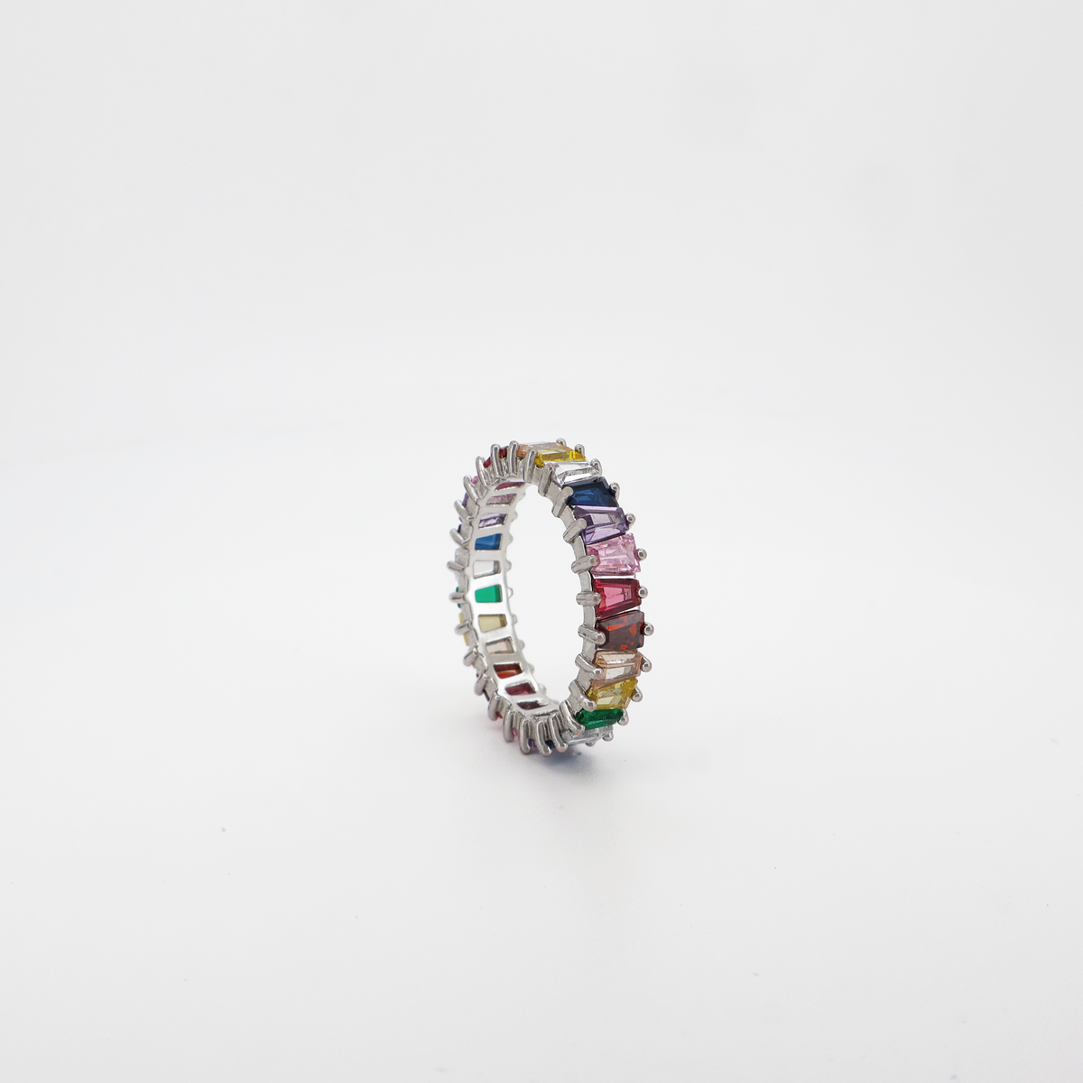 A multicolored baguette cut eternity ring with a high-polished finish on a white background.