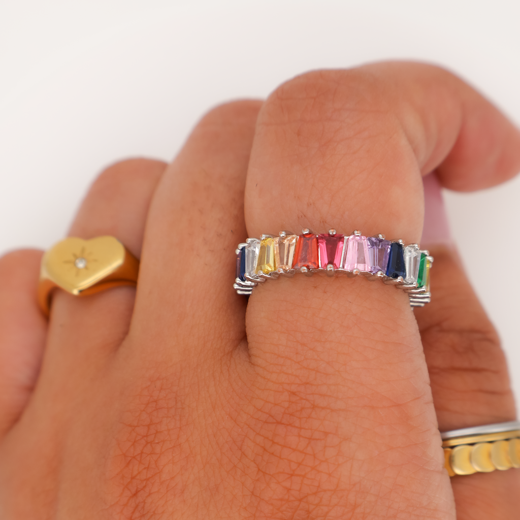 Multicolor baguette-cut crystal band ring in silver, worn on a finger against a white background