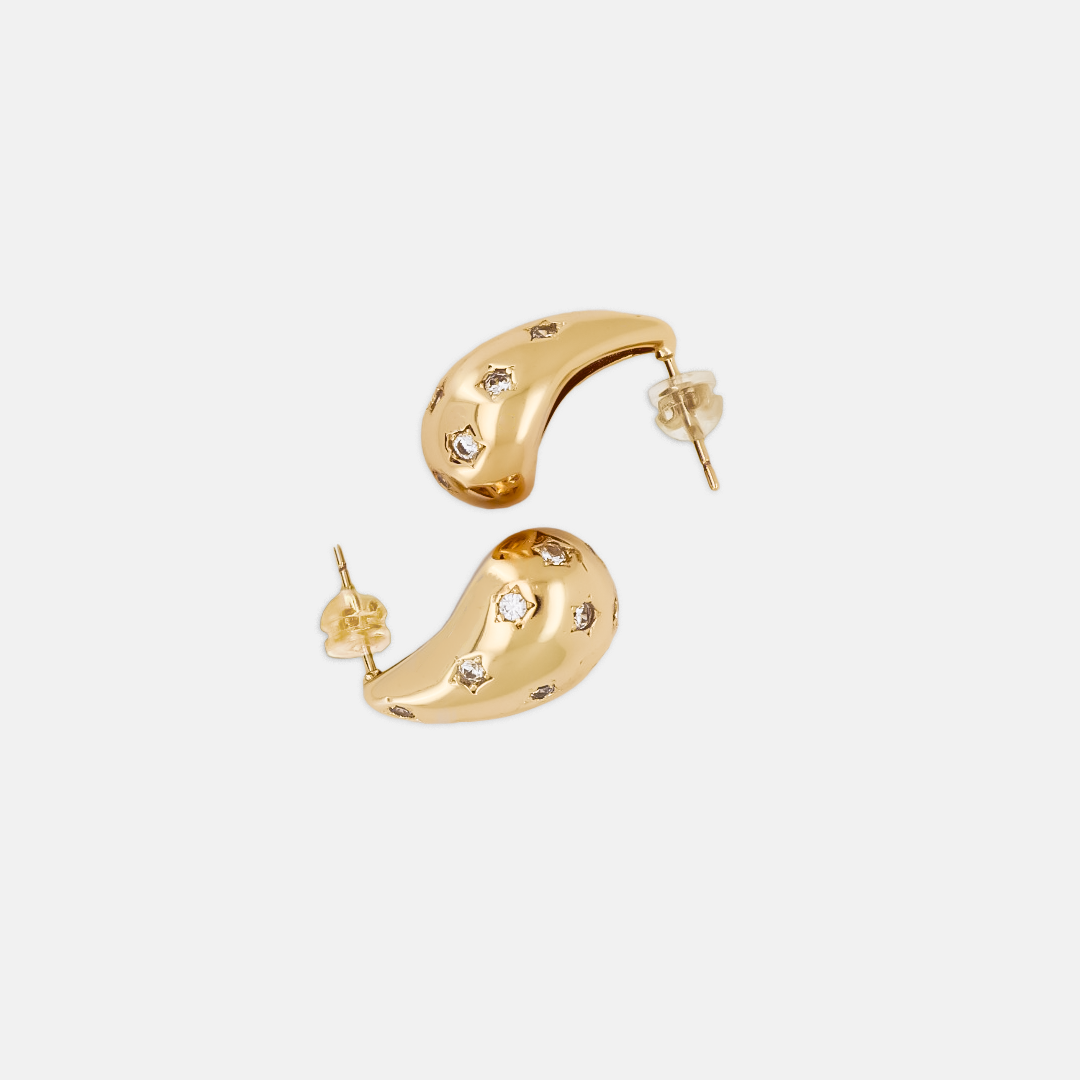 A pair of gold-plated brass earrings with star-like crystal accents, displayed against a white background.