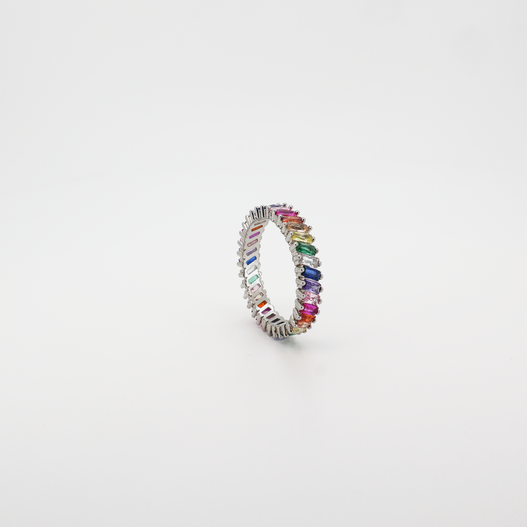 Angled view of a silver eternity band ring set with multicolor baguette-cut crystals, photographed on a white background