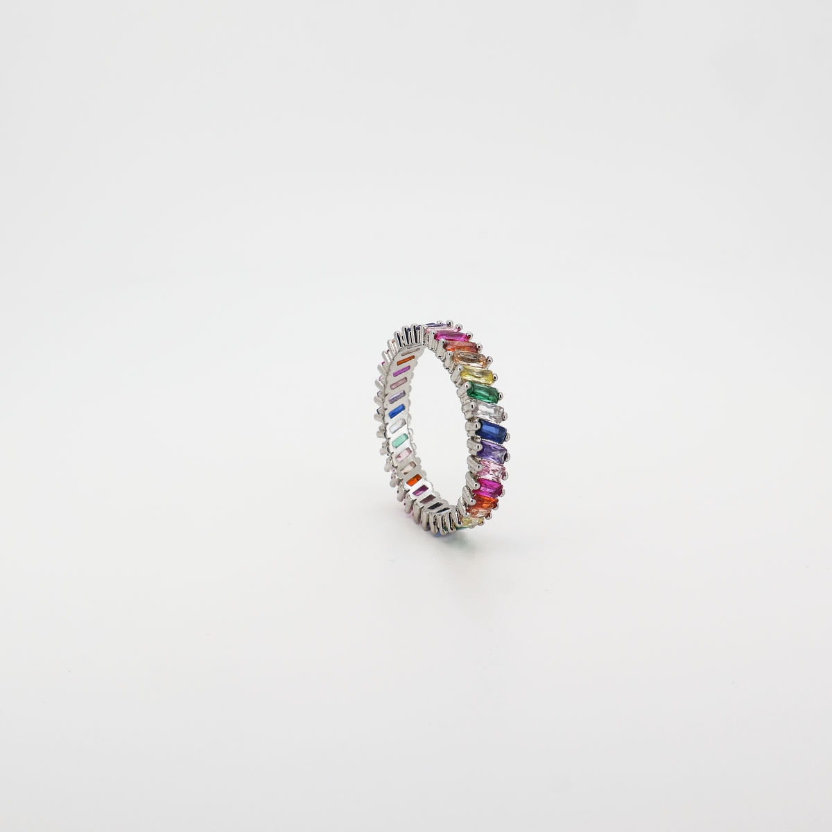 Angled view of a silver eternity band ring set with multicolor baguette-cut crystals, photographed on a white background