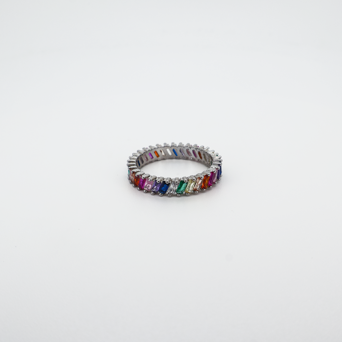 Silver band ring set with multicolor baguette-cut crystals, photographed on a white background.